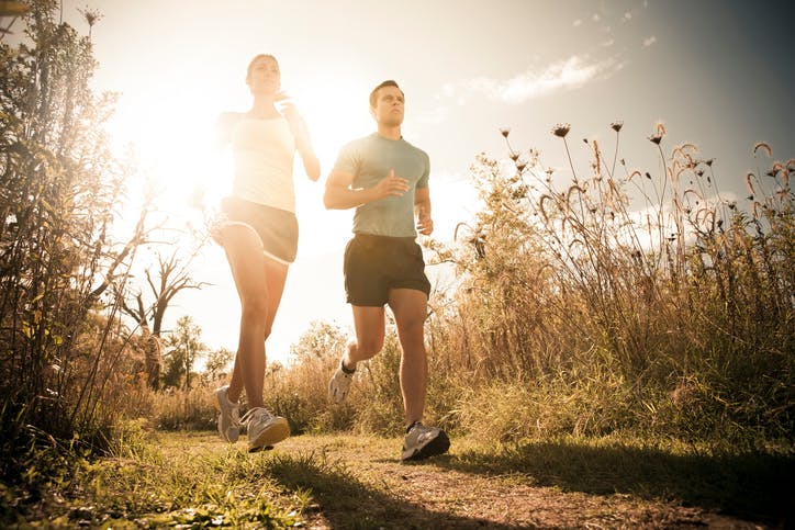 Man and woman jogging together on an outdoor trail.