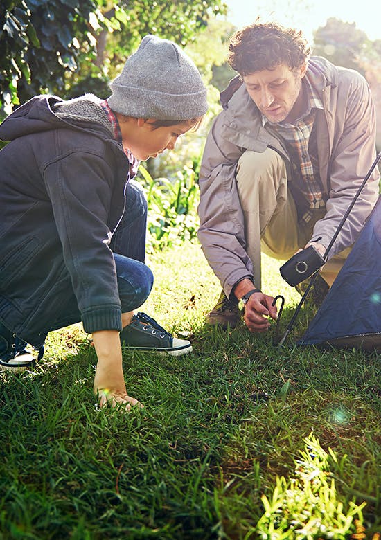 A man and a kid setting up a camping tent