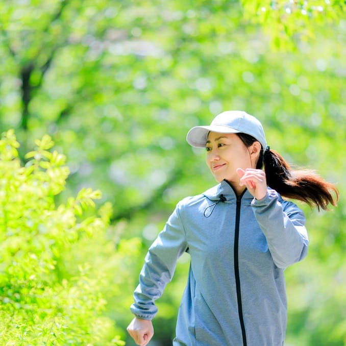 新緑の中をジョギングする女性
