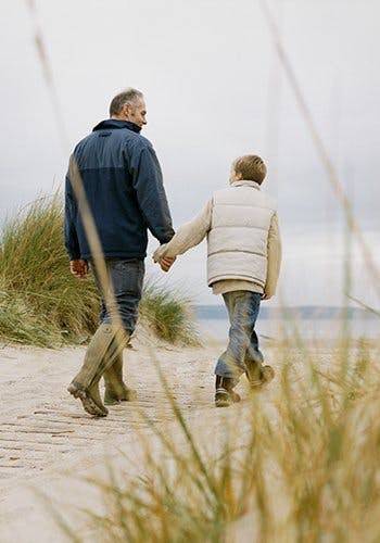 Przyczyny bólu - ojciec z synem idą za rękę po plaży