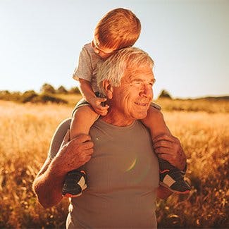 Poznaj swoje ciało i dowiedz jak zmienia się z wiekiem - dziadek niesie wnuczka na barana spacerując po polu.