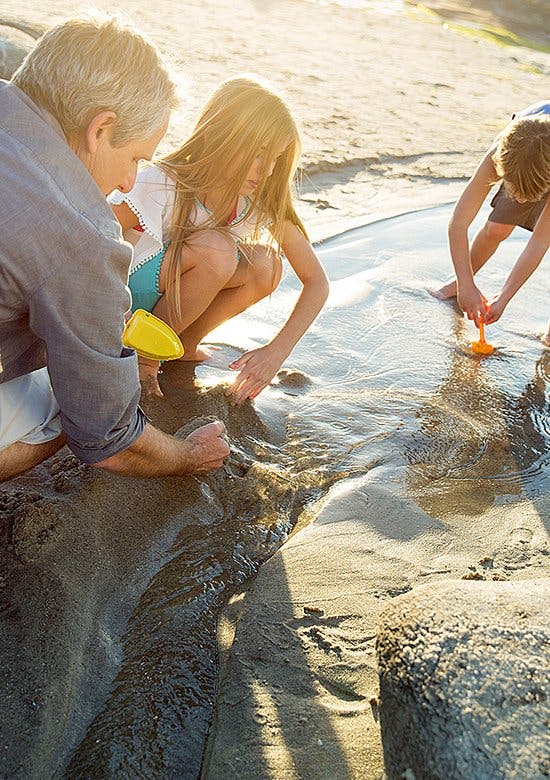 Odkryj radość płynącą z ruchu - ojciec z dziećmi bawią się łopatkami na plaży