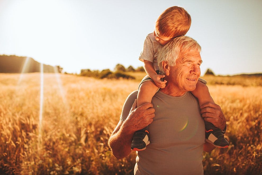 Poznaj swoje ciało i dowiedz jak zmienia się z wiekiem - dziadek niesie wnuczka na barana spacerując po polu.