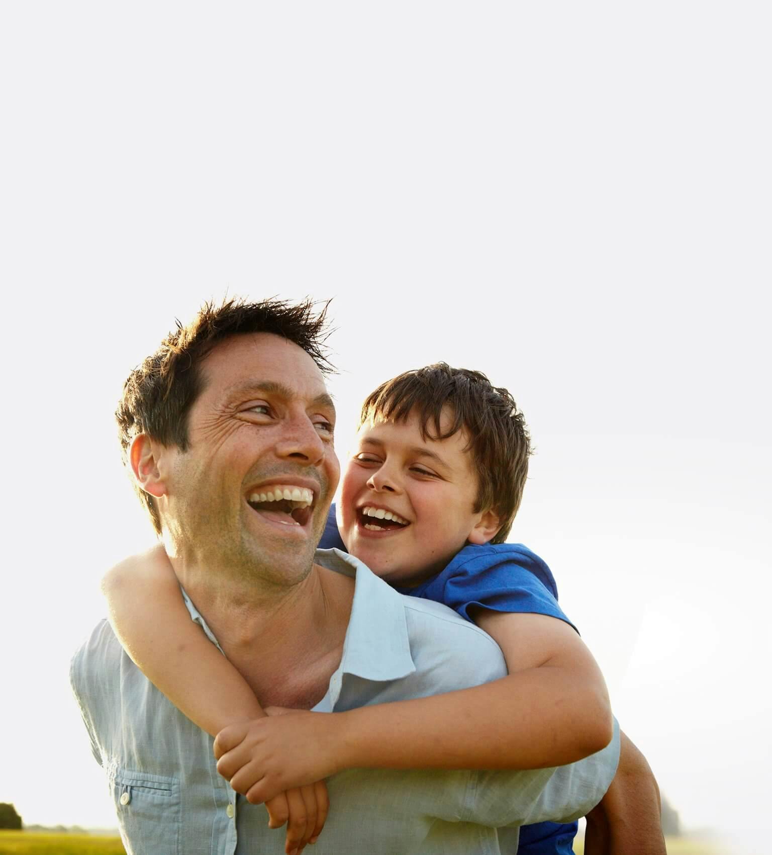 Uśmiechnięty ojciec trzymający na plecach swojego zadowolonego syna