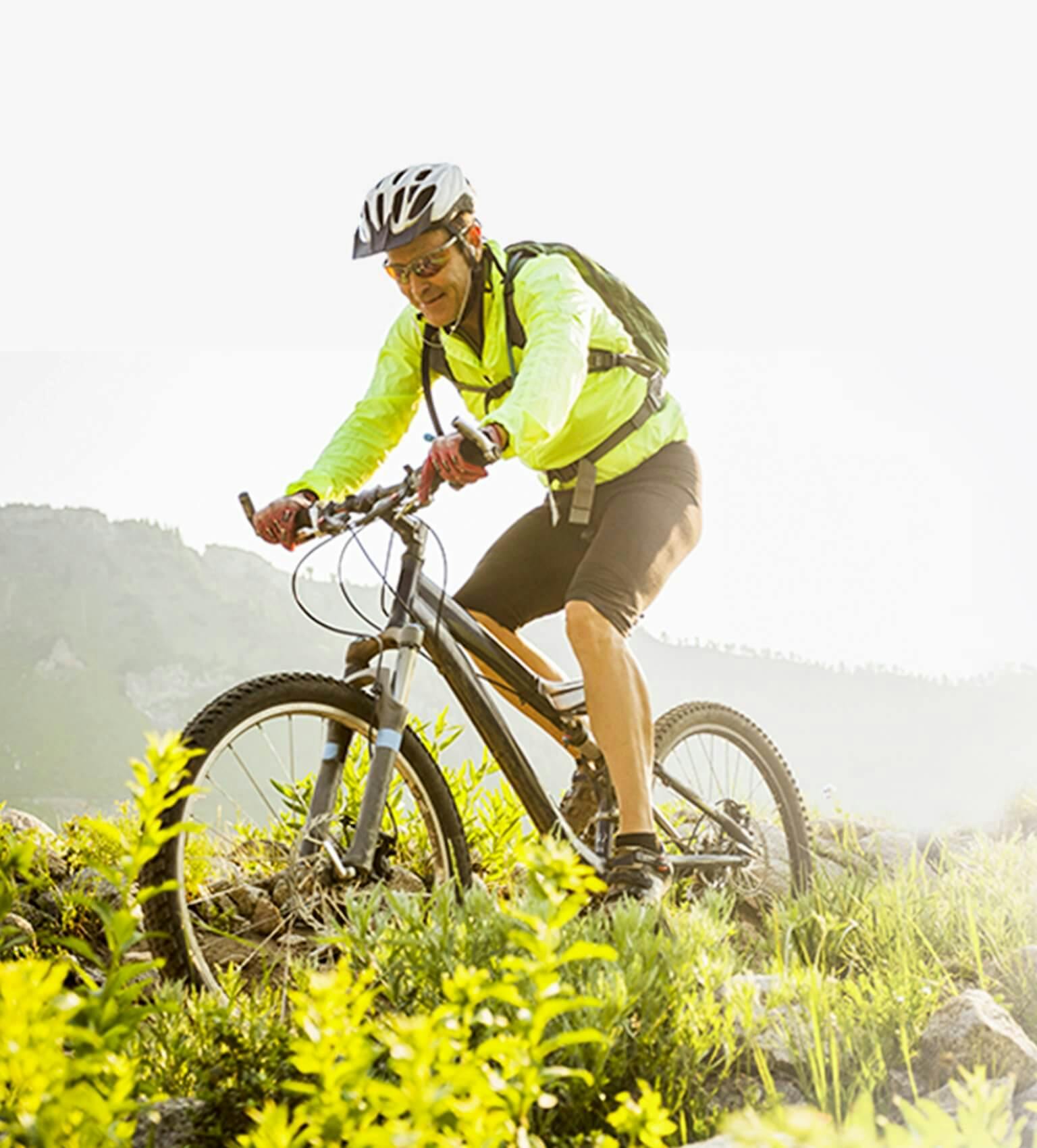 Mężczyzna na rowerze górskim w scenerii gór i łąki