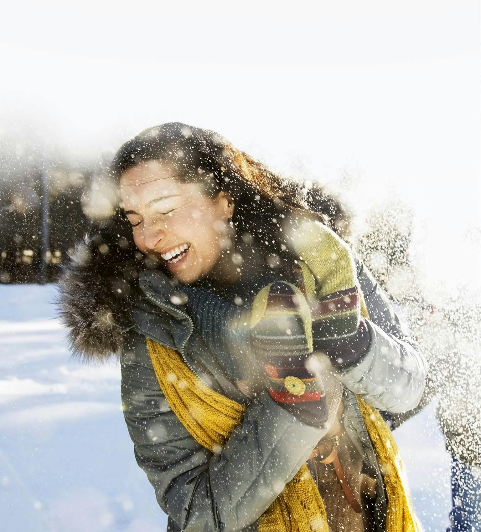 Uśmiechnięta, ciepło ubrana kobieta w zimowej scenerii