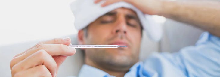 una imagen de un hombre con gripe que mide temperatura con un termómetro