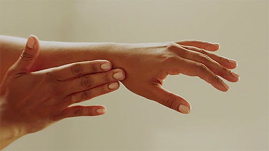 dos manos femeninas haciendo movimientos de masaje sobre el fondo claro