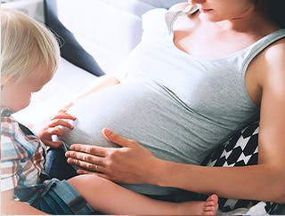 Femme enceinte avec son bambin sur les genoux