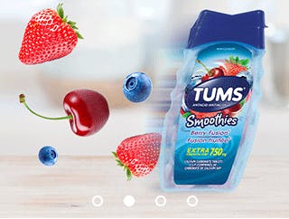 Bottle of Tums smoothies with cherries, blueberries and strawberries behind it