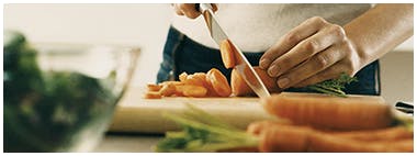 Woman cutting up carrots on wooden cutting boards