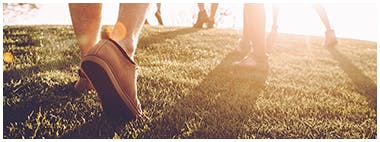 Close up of people’s shoes exercising on a grass field