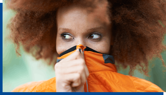 Woman in orange coat covering her face due to cold sores Woman in orange coat covering her face due to cold sores