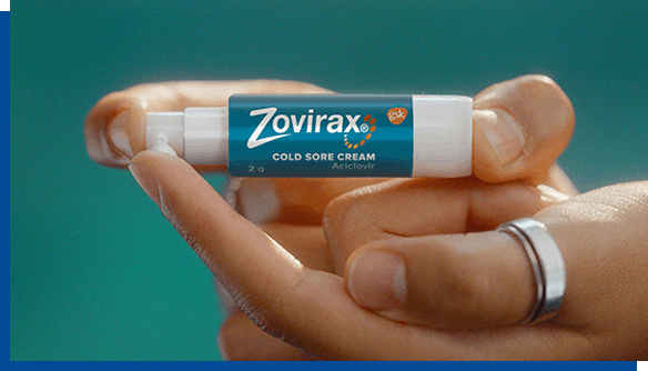Person with ring on finger holding Zovirax Cold Sore Cream pump