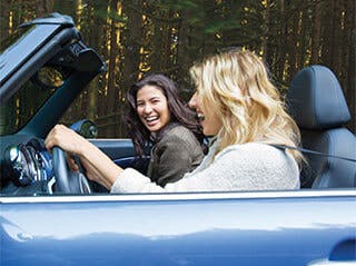 Dvě ženy, které jedou autem a smějí se