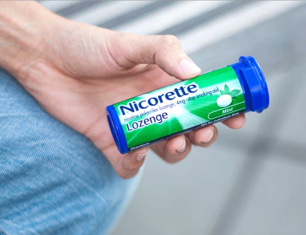 Hand holding a container of Mint flavored Nicorette lozenges