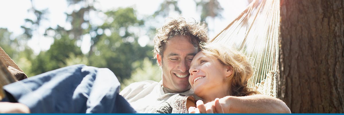 Couple holding hands and smiling in hammock