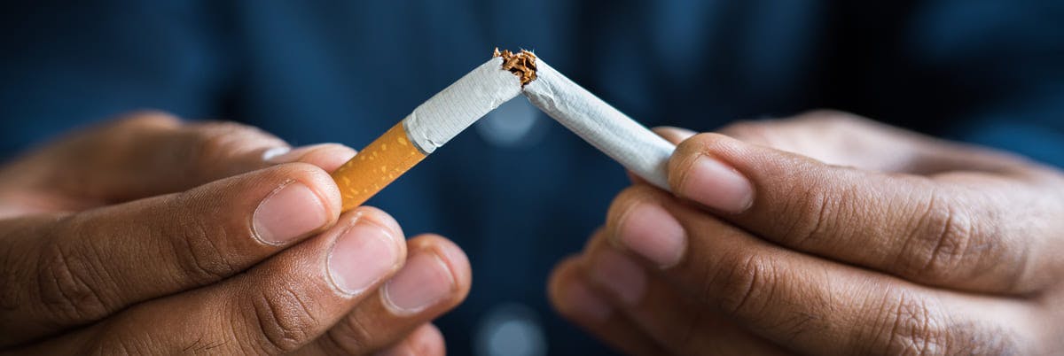 Pair of hands breaking a cigarette in half