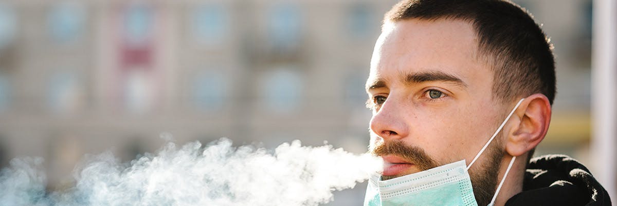 man with mask blowing smoke